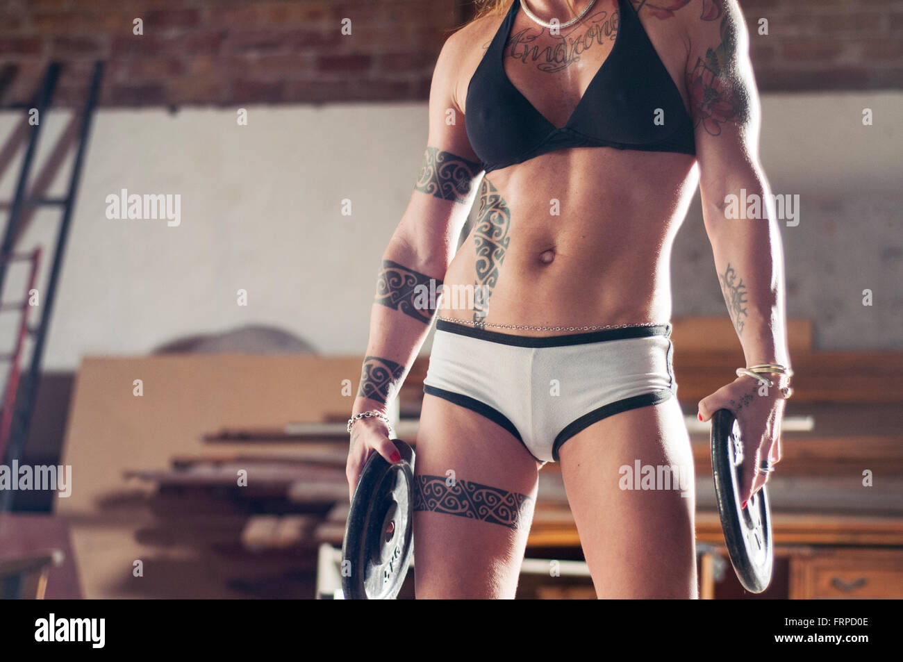 Athletische tätowierte Frau Gewichte in ihren Händen hält. Stockfoto