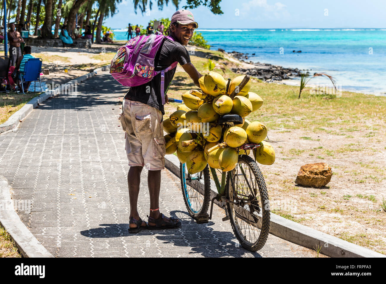 Mauritius-junger Mann verkauft Kokosnüsse von seinem Fahrrad am Strand Blue Bay, Mauritius. Stockfoto
