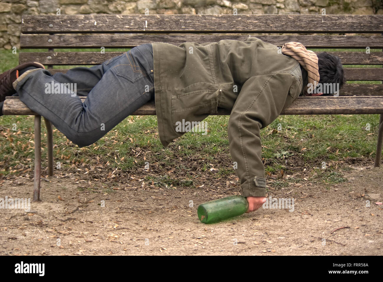 betrunken Bettler schlafen auf einer Bank mit einer Flasche in der hand ...