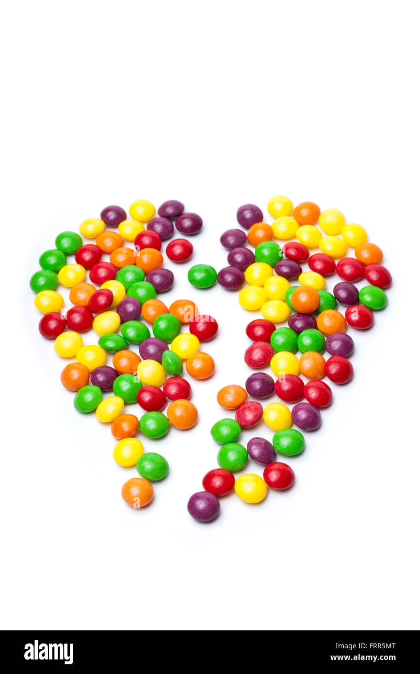 bunten Süßigkeiten auf weißem Hintergrund in gebrochenes Herzform Stockfoto