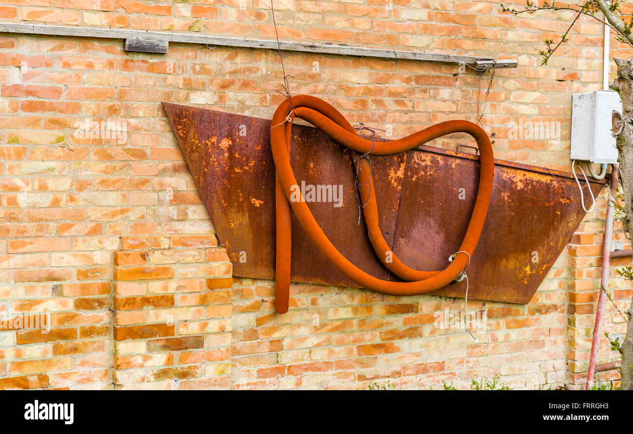 eine alte orange Gummischlauch an der Wand ein peeling Stockfoto