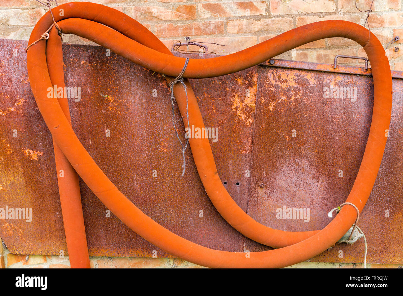 eine alte orange Gummischlauch an der Wand ein peeling Stockfoto