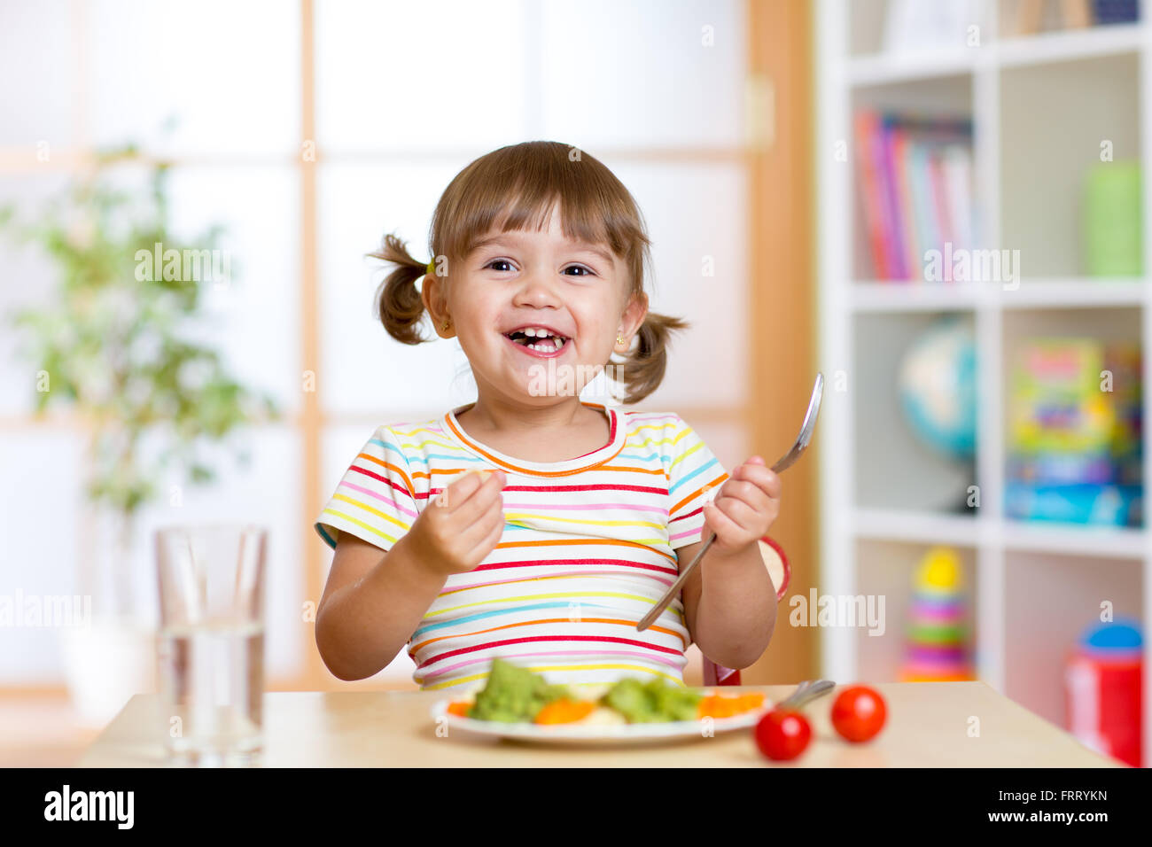 Glückliches Kind Mädchen essen Gemüse. Gesunde Ernährung für Kinder Stockfoto