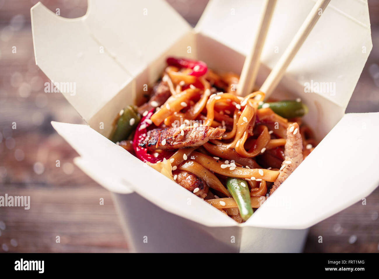 Nudeln mit Schweinefleisch und Gemüse in Take-out Box auf Holztisch Stockfoto