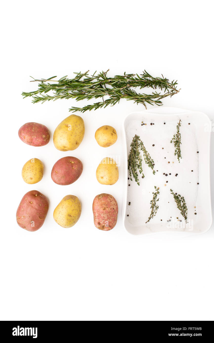 Rohe Kartoffeln mit Gewürzen und Kräutern auf dem weißen Hintergrund vertikale Stockfoto