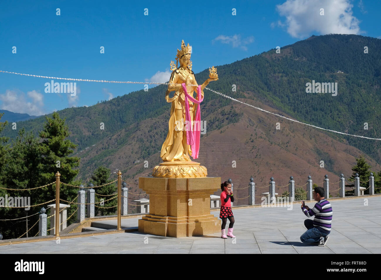Mädchen posiert für ein Foto von einer Statue einer buddhistischen Göttin am Buddha Dordenma Standort, Thimphu, Bhutan. Stockfoto