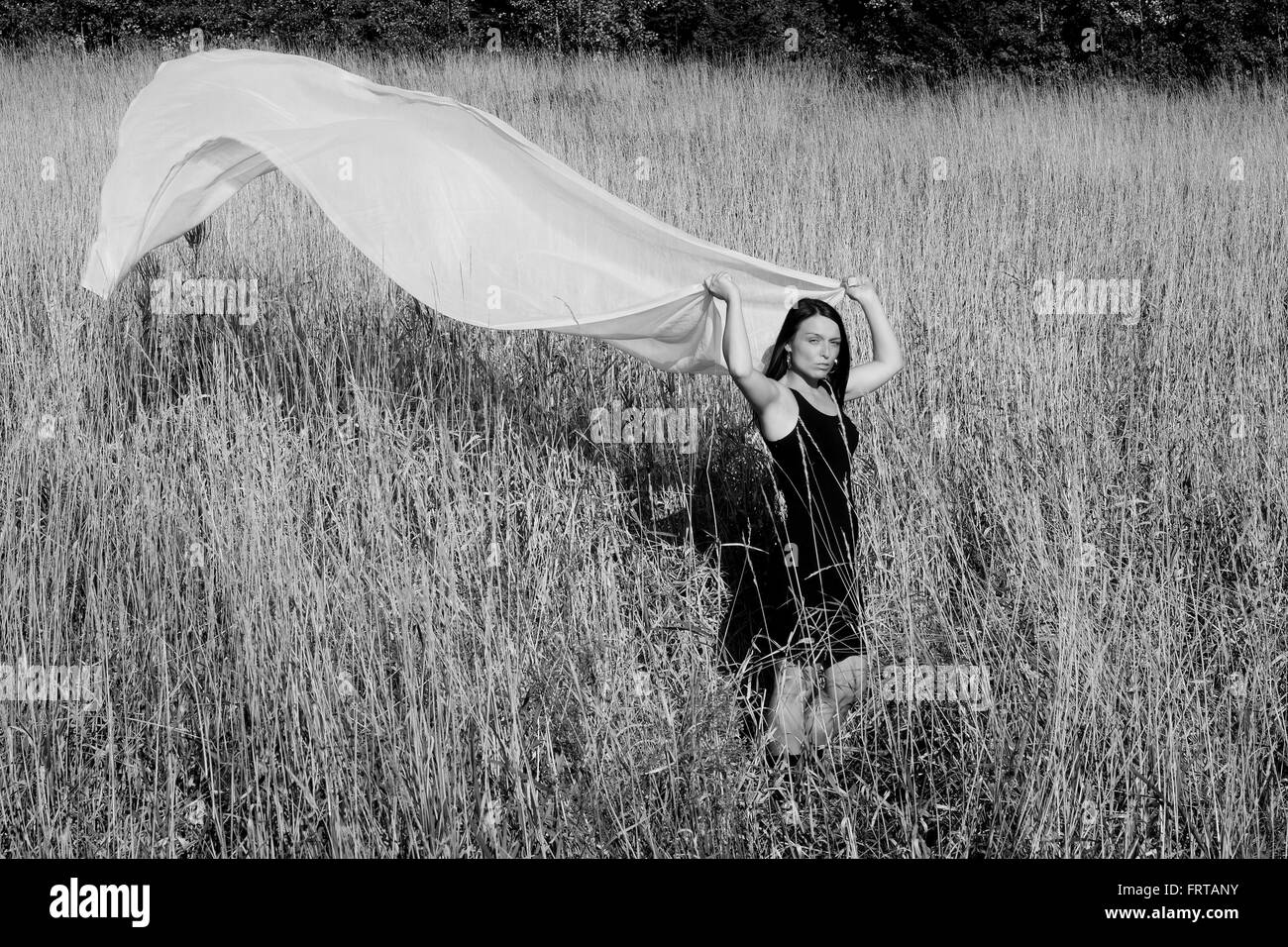 Schwarz / weiß-Bild von einer hübschen Frau trug ein schwarzes Kleid mit einer Länge von weißem Stoff fließt hinter ihr. Stockfoto