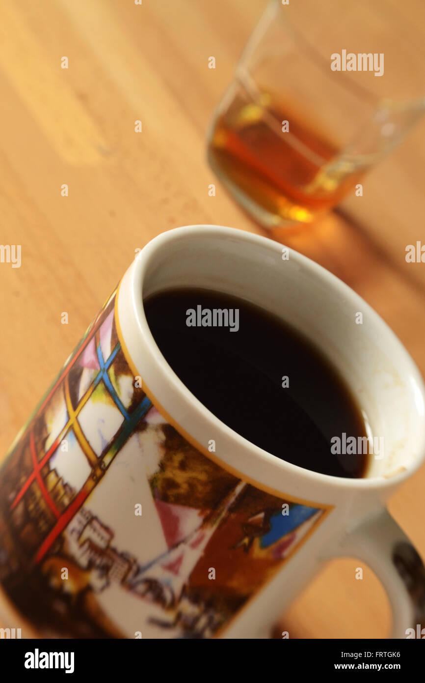 Tasse Kaffee mit einem Schuss Scotch im Hintergrund. Schuss mit LensBaby für Tiefenschärfe. Stockfoto