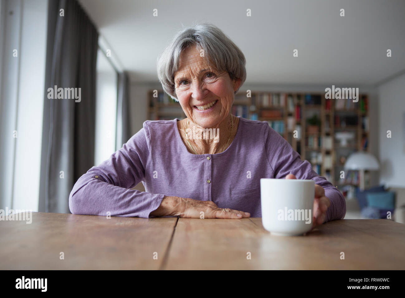 Porträt von senior Frau mit Tasse Kaffee am Tisch sitzen Stockfoto