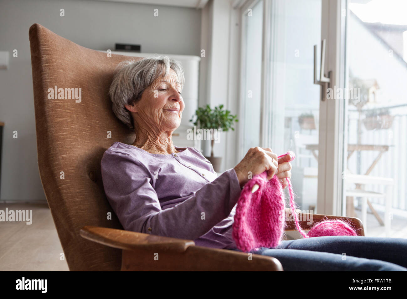 Porträt von senior Frau sitzt auf Sessel zu Hause stricken Stockfoto