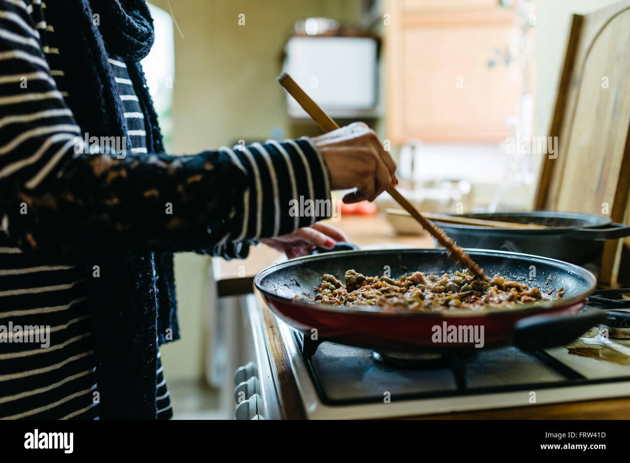 Frau, die das Kochen auf Gas-Herd in ihrer Küche, Teilansicht Stockfoto