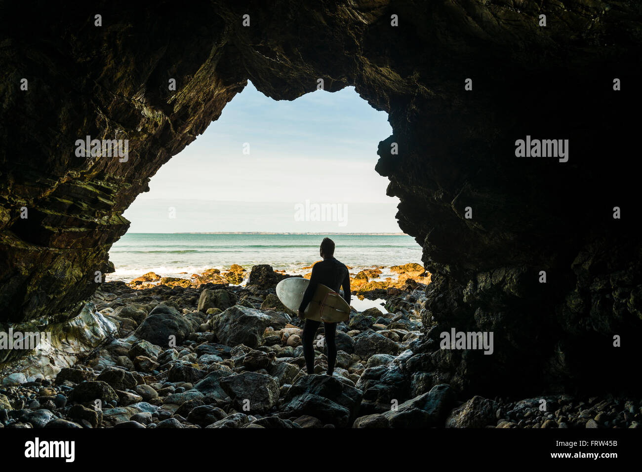 Frankreich, Bretagne, Finistere, Halbinsel Crozon, Mann auf felsigen Strand mit Surfbrett Stockfoto