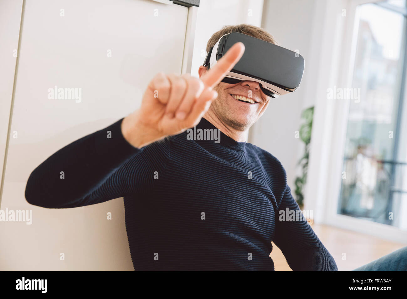 Lächelnder Mann mit virtual-Reality-Brille zeigte mit dem finger Stockfoto