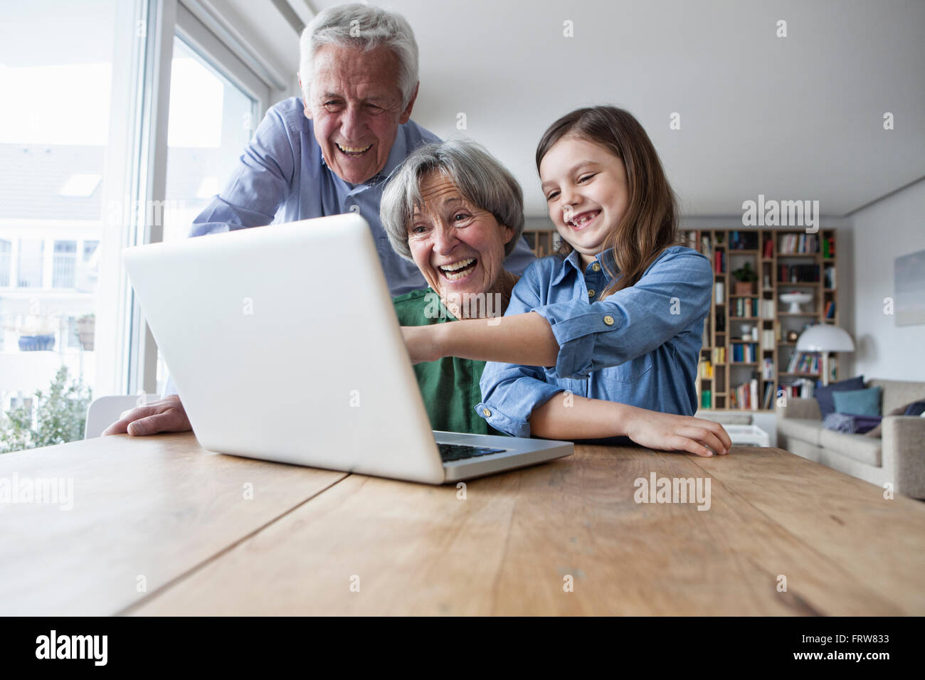 Großeltern und ihre Enkelin Spaß mit Laptop zu Hause Stockfoto