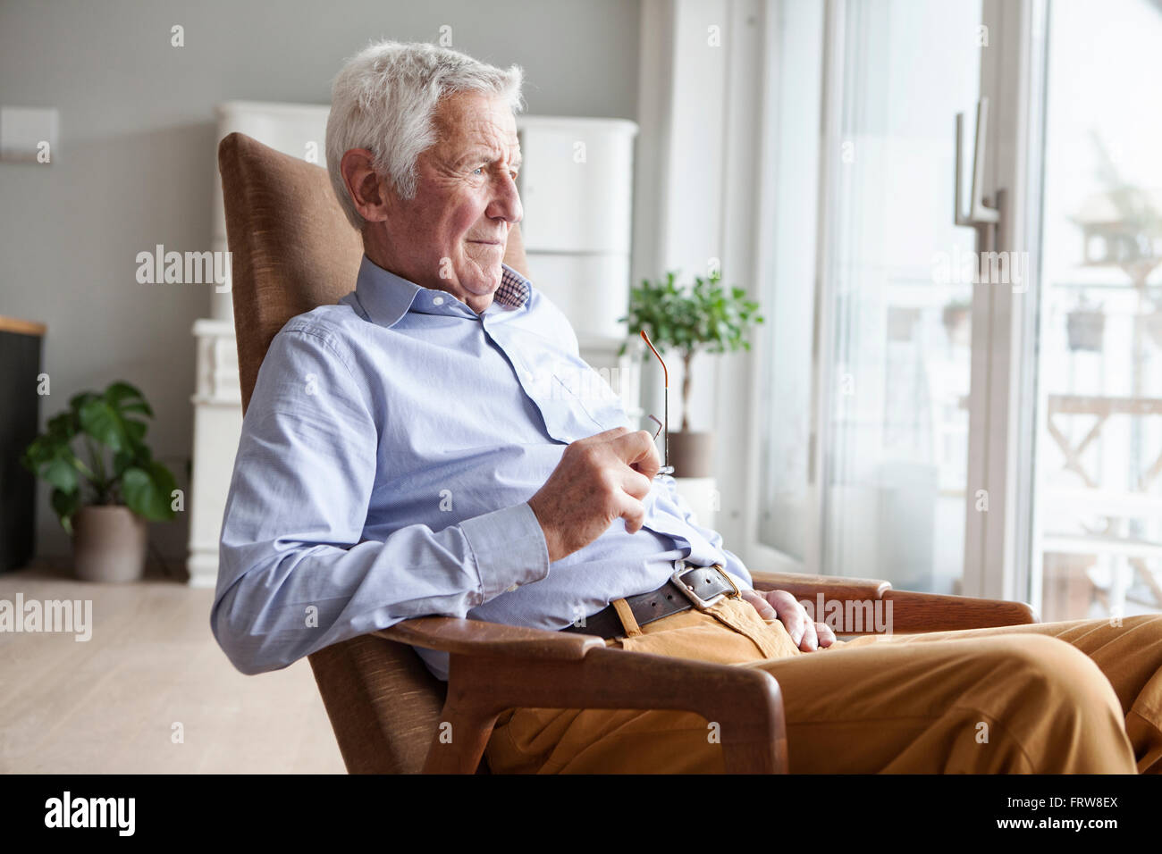 Porträt von senior Mann sitzt auf Sessel zu Hause Blick durch Fenster Stockfoto
