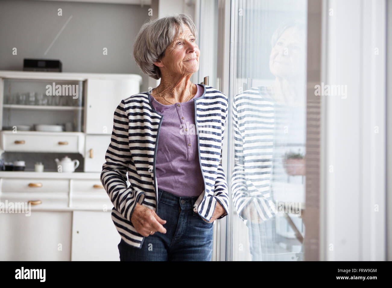 Porträt von senior Frau Blick durch Fenster zu Hause Stockfoto