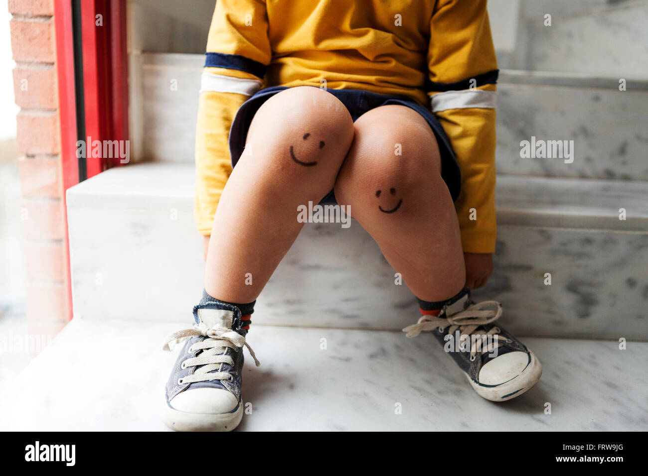 Junge Sitzt Auf Der Treppe Mit Smiley Gesichter Auf Den Knien Stockfotografie Alamy