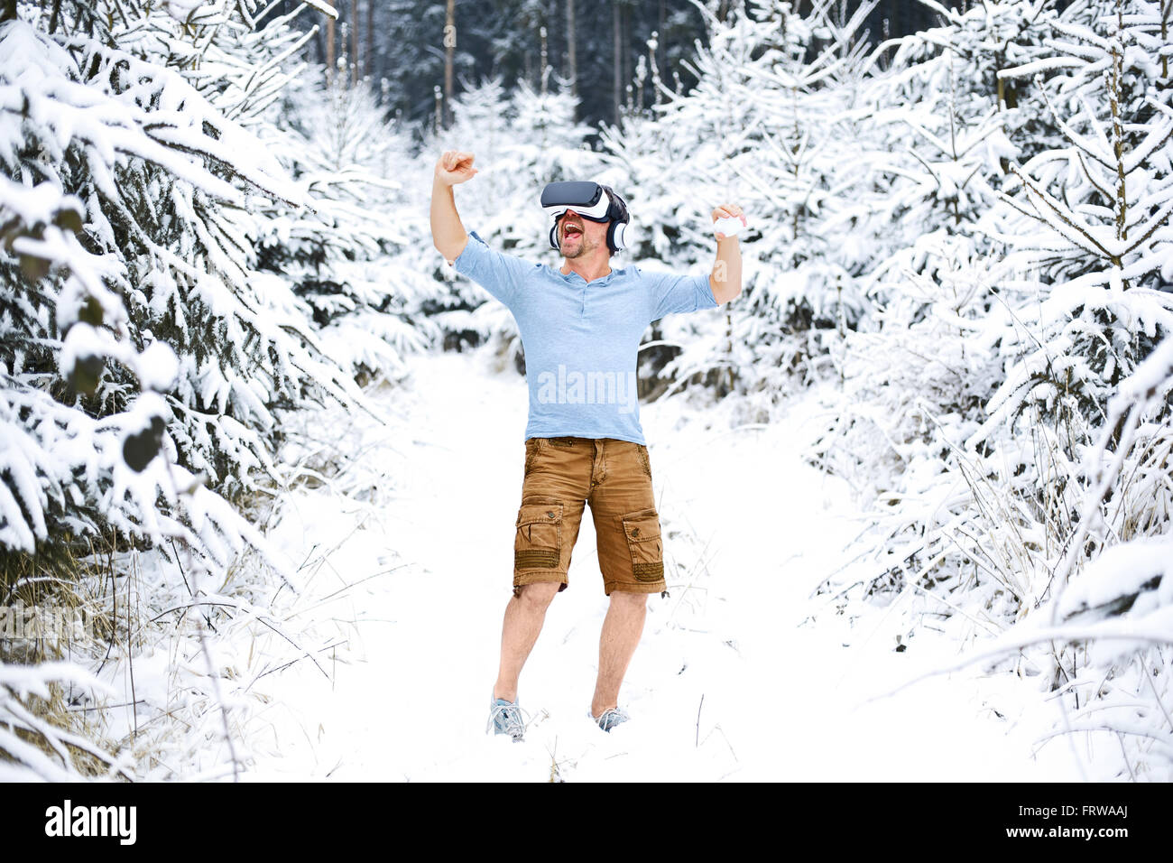 Glücklicher Mann tragen Virtual-Reality-Brille in Winterlandschaft Stockfoto