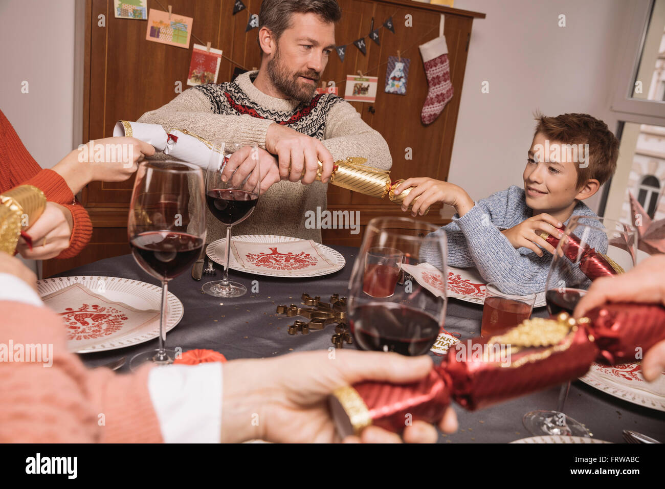 Enden der Christmas Cracker ziehen am Familientisch Stockfoto
