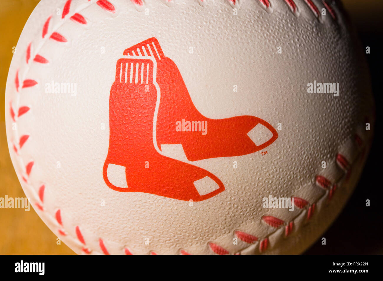 Weißer Kautschuk Baseball mit den Boston Red Sox-Logo auf der Seite zusammen mit roten Nähten, ruht auf einem Holztisch gedruckt Stockfoto