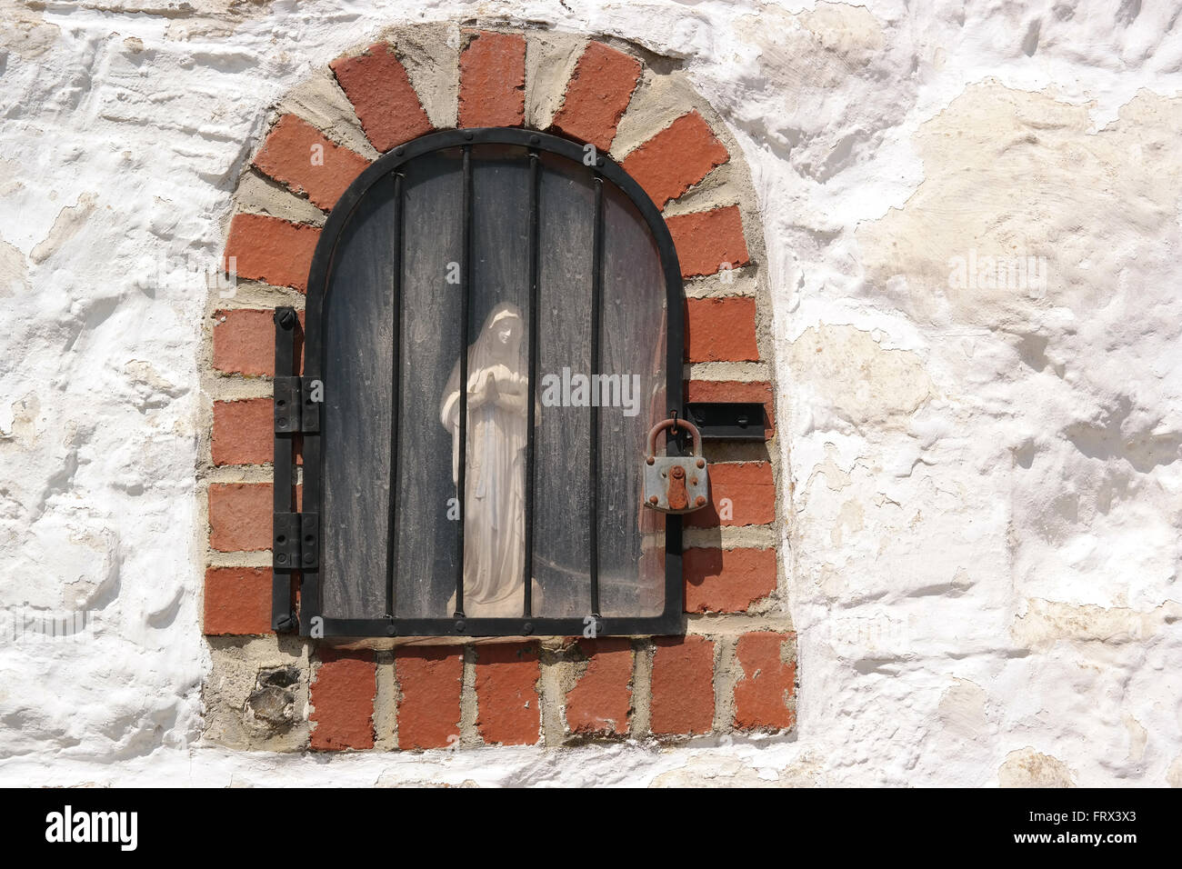 Jungfrau Maria gesperrt hinter Bars und Vorhängeschloss. Stockfoto