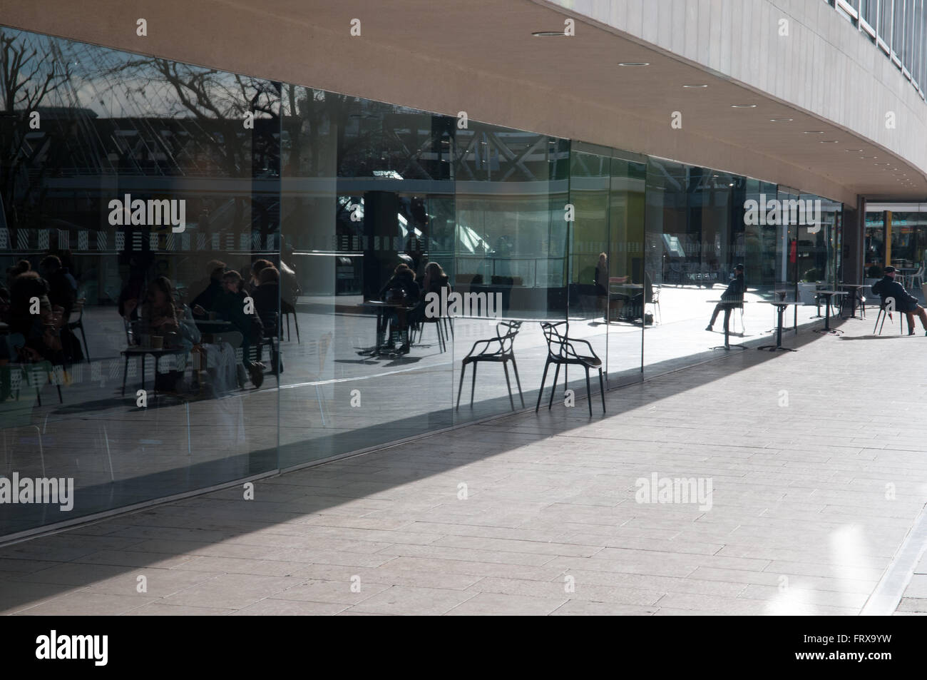 Reflexionen in einem Café-Fenster als Menschen in der Sonne entspannen Stockfoto