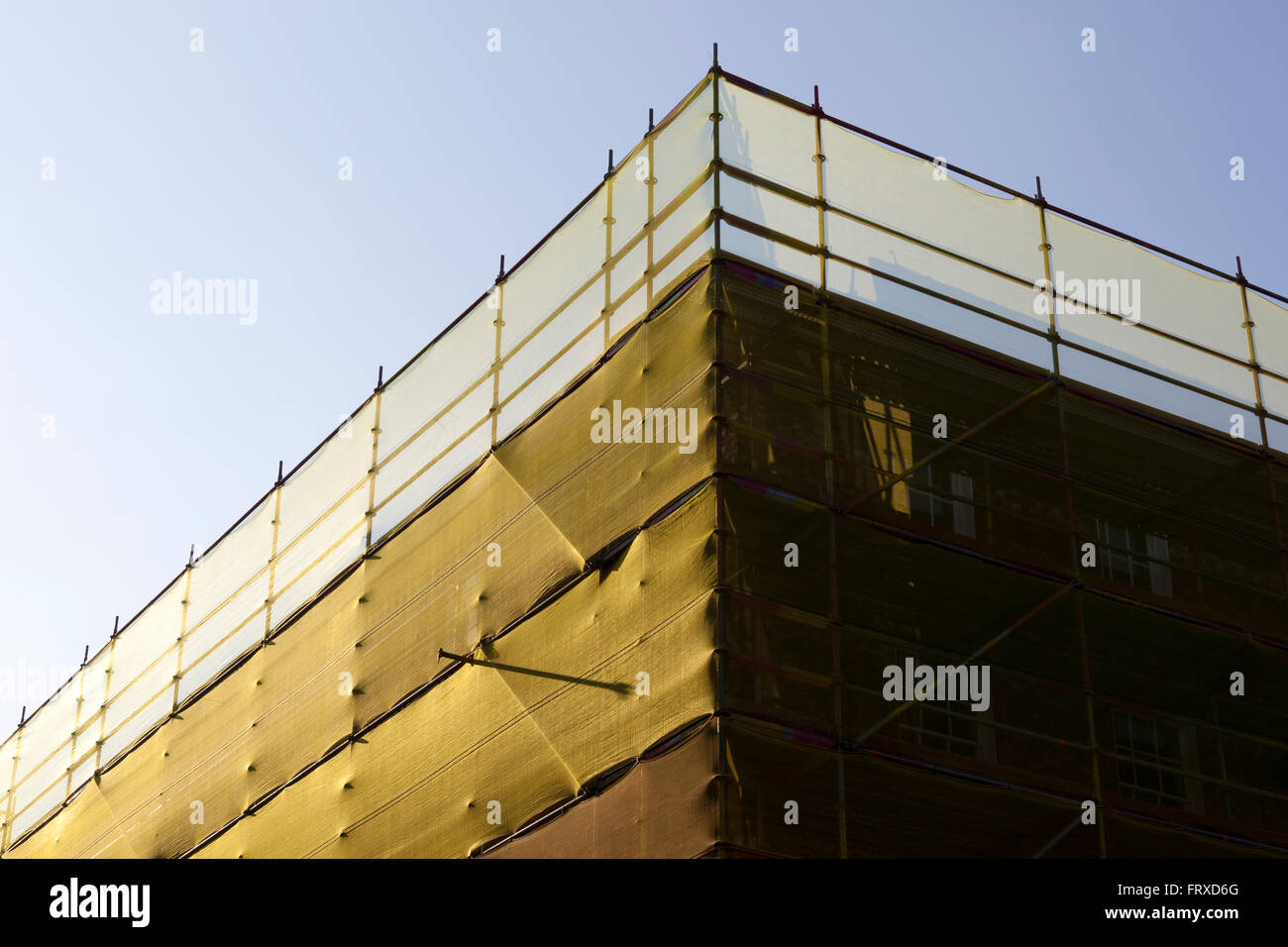 Die Seite eines Gebäudes der Stadt bedeckt im Gerüstbau und verpackt in Filetarbeit. Stockfoto