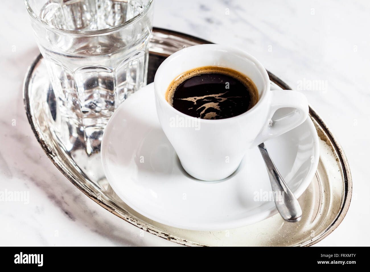 Tasse Espresso und ein Glas Wasser auf Metalltablett Stockfoto