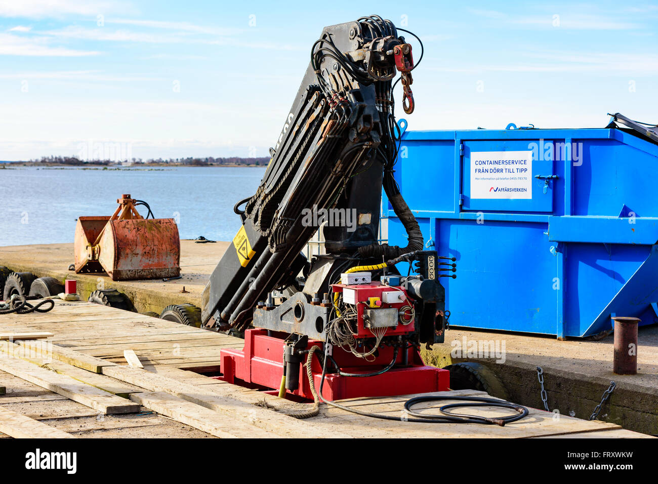 Torhamn, Schweden - 18. März 2016: Ein Baukran ist an einem Schwimmer für den Einsatz bei der Aufhebung der im Meerwasser montiert. Pier mit container Stockfoto