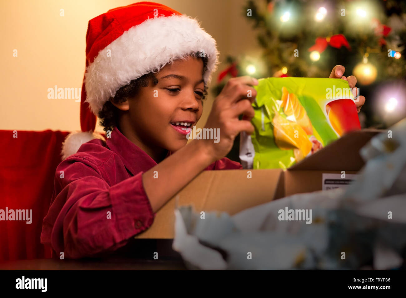 Glücklich Darkskinned junge öffnet vorhanden. Schwarze Kind öffnen Weihnachtsgeschenk. Genau das, was ich wollte. Weihnachten bringt Freude. Stockfoto