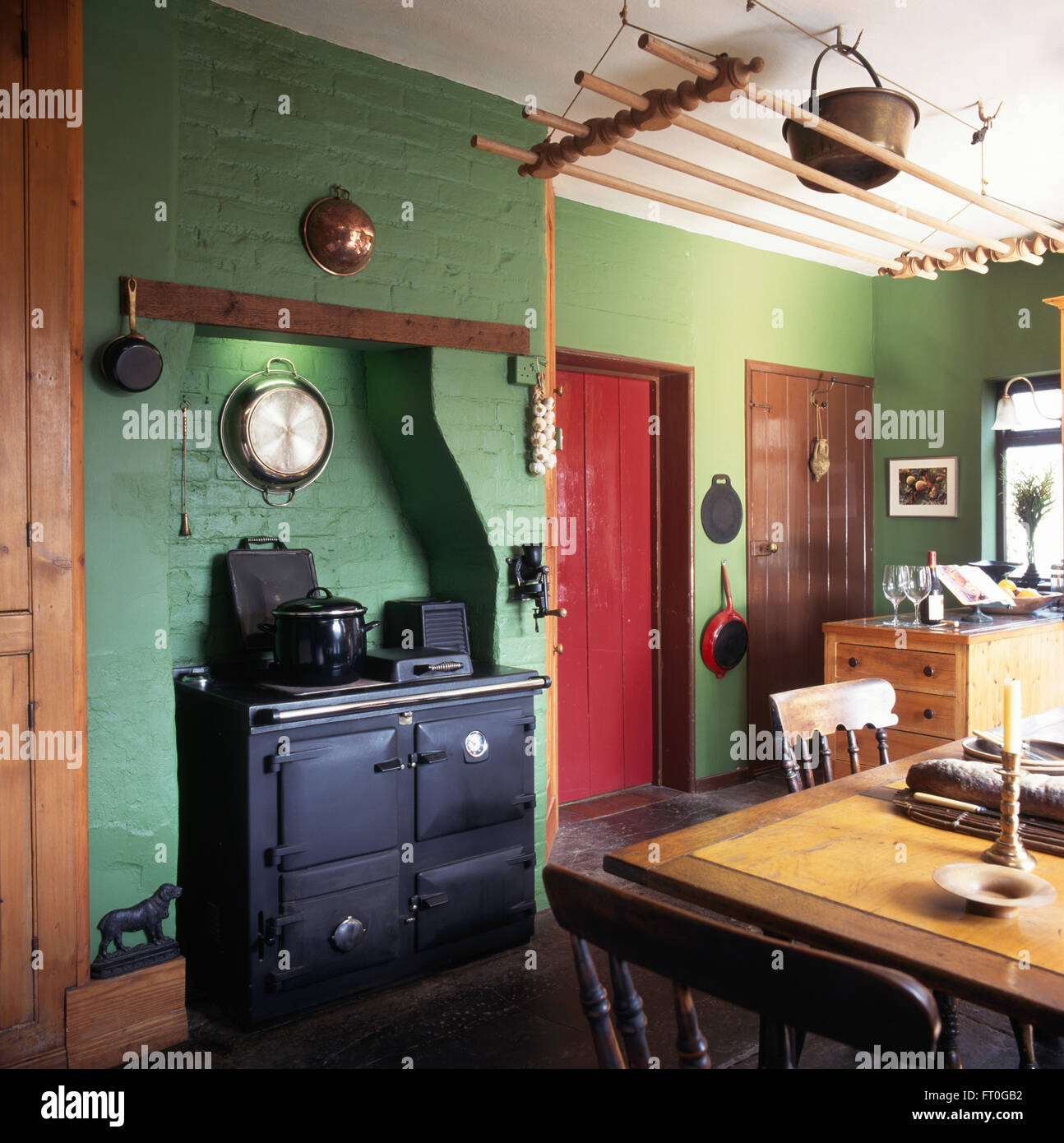 Schwarzen Herd in grüne Landhausküche mit einem Vintage Riemenscheibe Maid Trockner Stockfoto