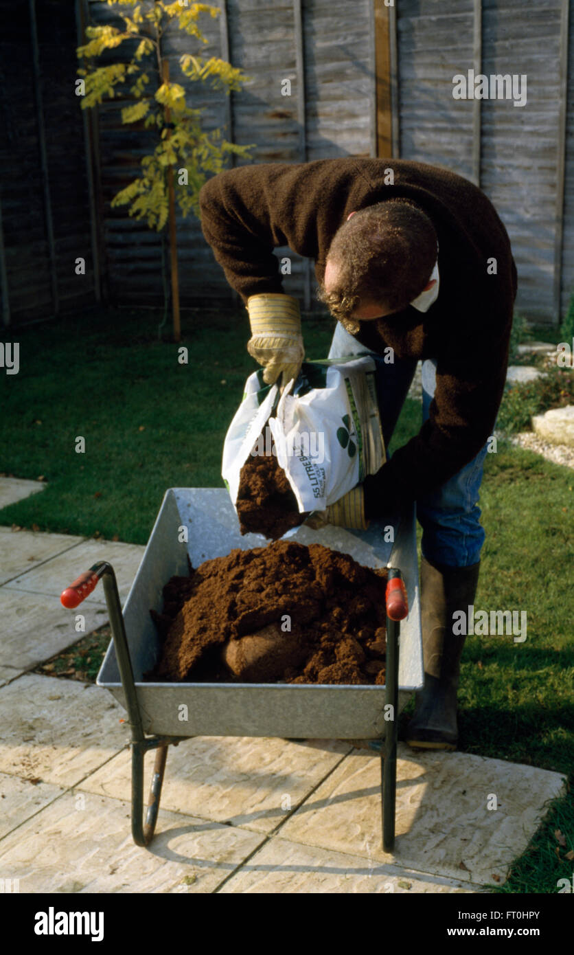 Gärtner, Kompost aus einem Plastiksack in eine Schubkarre für nur zur redaktionellen Nutzung Stockfoto