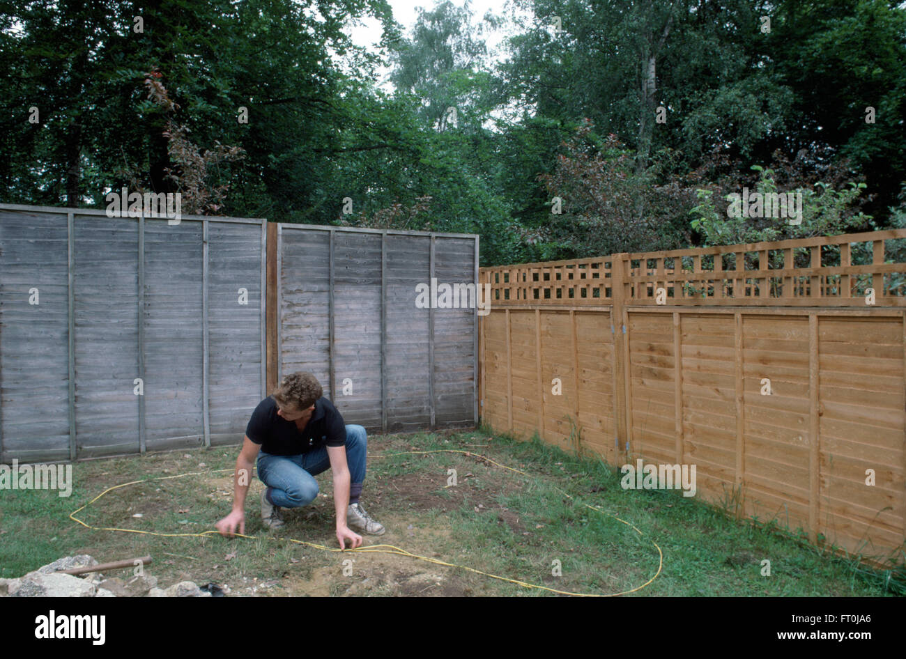 Gärtner, die Messung der Bereich für einen Steingarten in Ecke eines Rasens für nur zur redaktionellen Nutzung Stockfoto