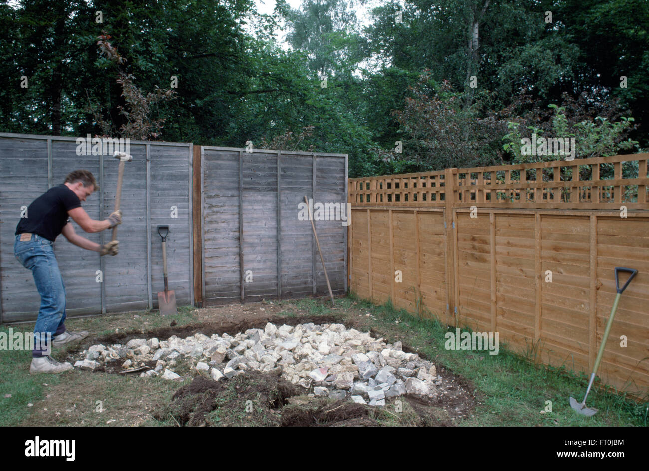 Gärtner mit einem Holzhammer, Felsen zu Form ein neuer Steingarten-Bereich für nur zur redaktionellen Nutzung zu knacken Stockfoto