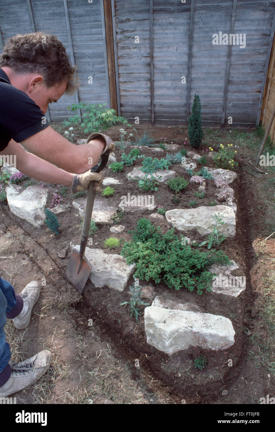 Nahaufnahme des Gärtners ausgraben Rand des neu gemacht und bepflanzten Steingarten für nur zur redaktionellen Nutzung Stockfoto