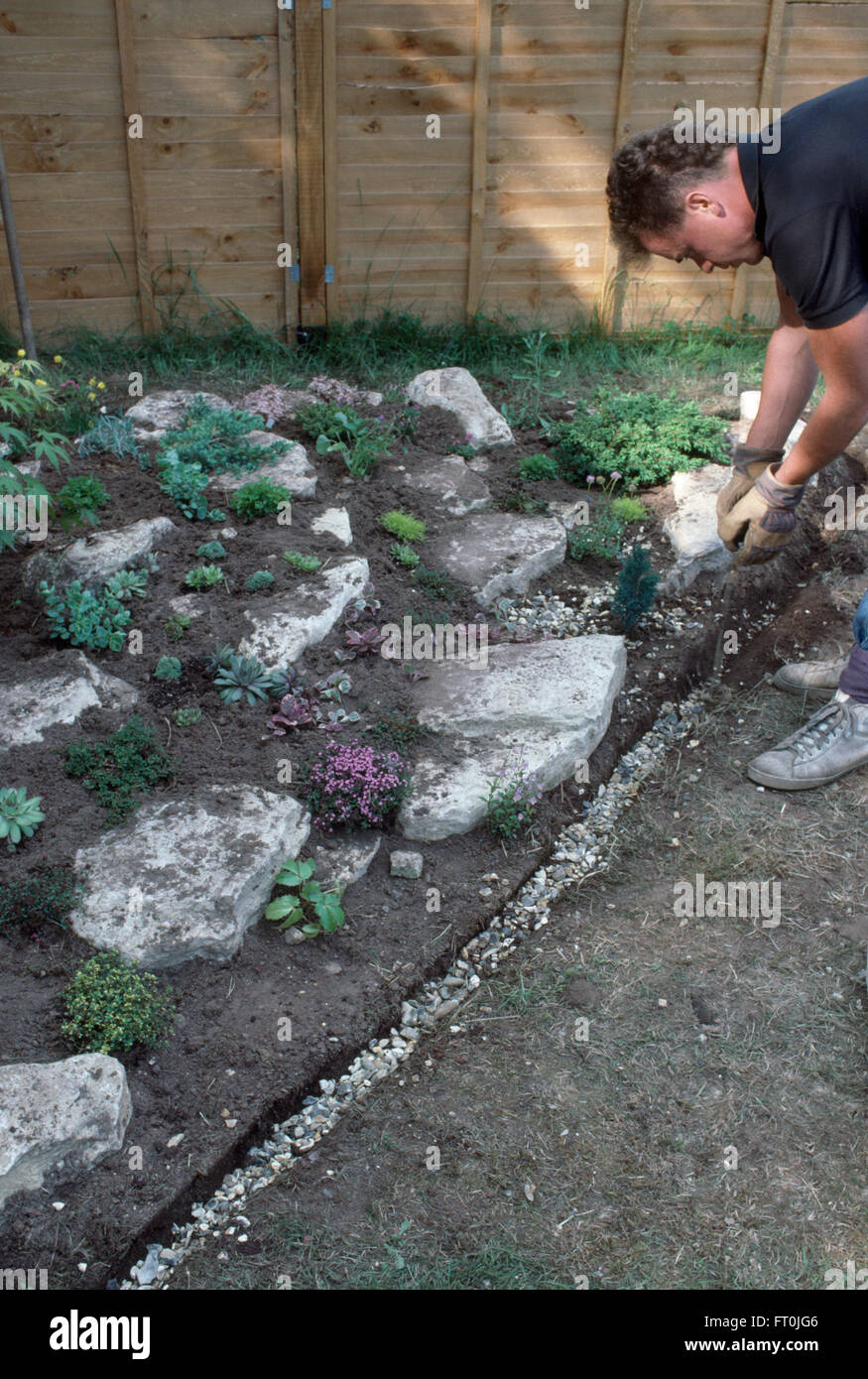 Gärtner eine schmale Kante Graben um eine neu angelegte Steingarten für redaktionelles Schindel hinzufügen Stockfoto