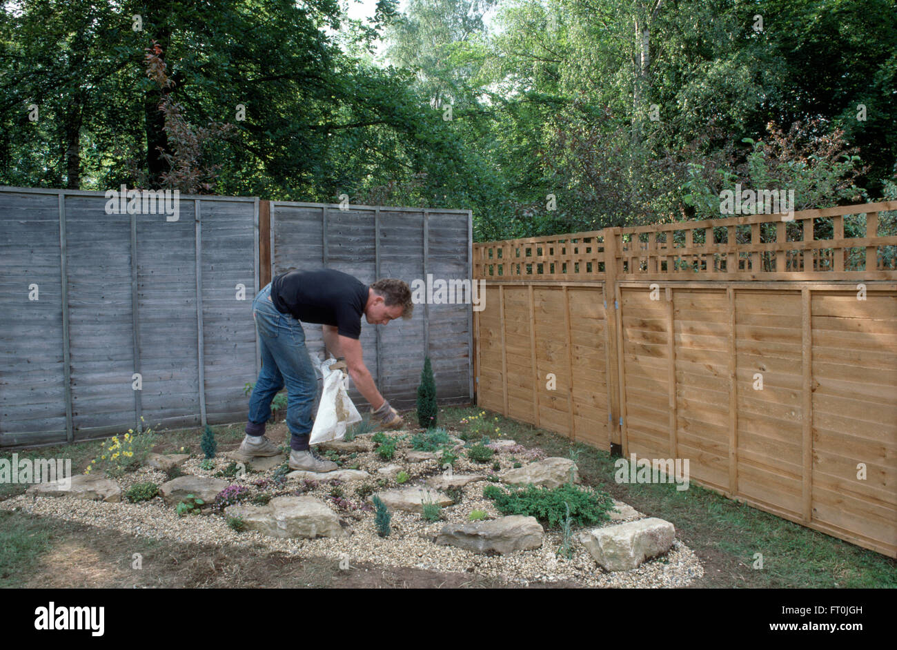 Gärtner eine neu angelegte Steingarten in einem neuen Garten für nur zur redaktionellen Nutzung Kies hinzufügen Stockfoto