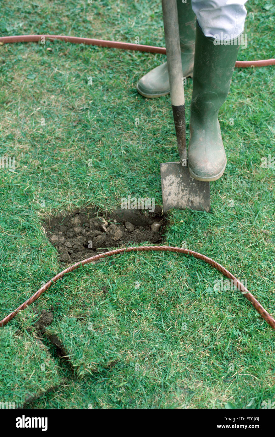 Nahaufnahme eines Gärtners ausgraben gemessene Fläche im Rasen für einen neuen Teich für nur zur redaktionellen Nutzung Stockfoto