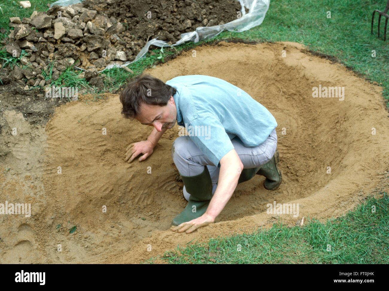 Nahaufnahme des Gärtners stopfen sich Sand in ausgegraben Bereich für einen neuen Teich für nur zur redaktionellen Nutzung Stockfoto