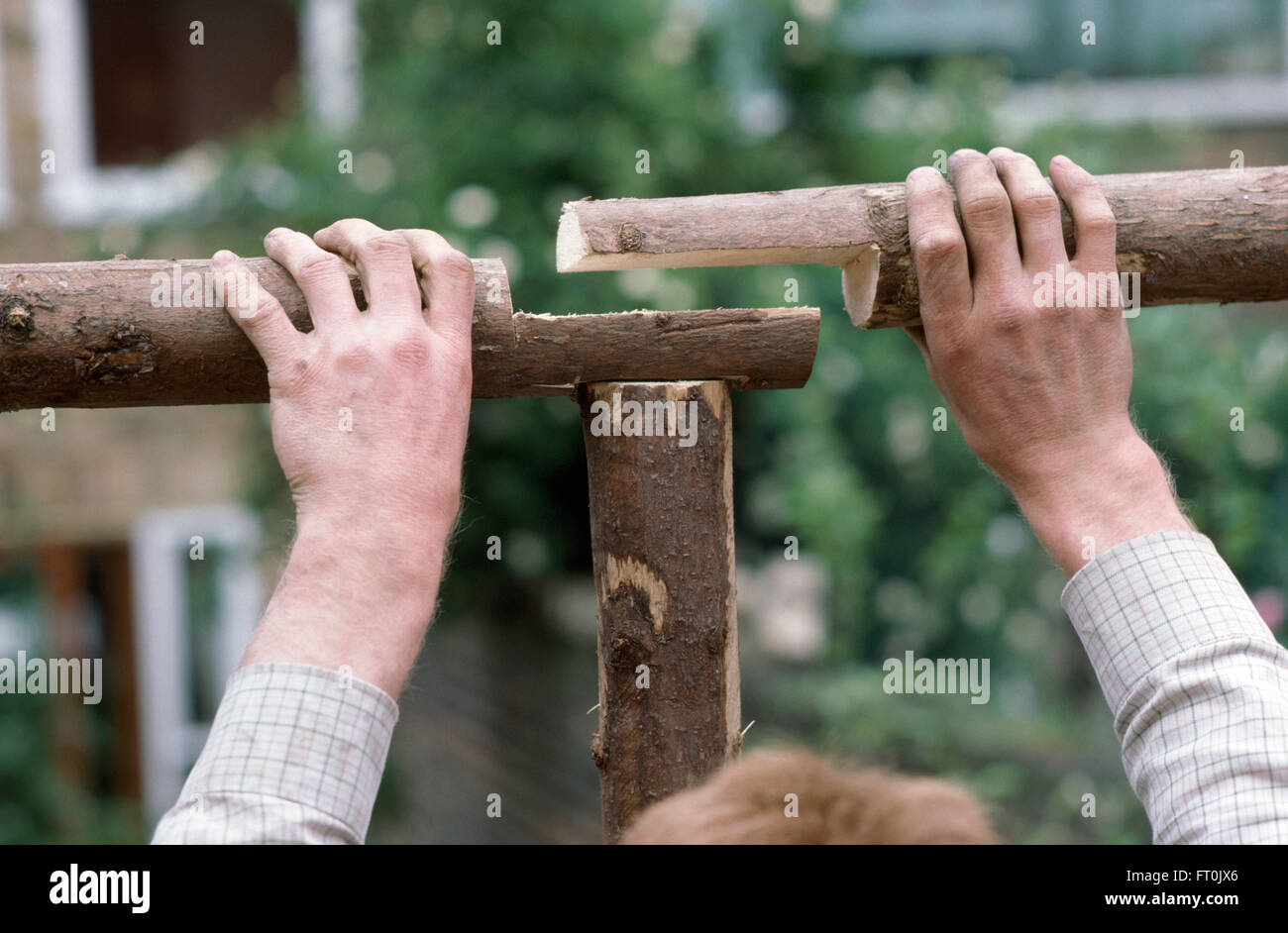 Nahaufnahme der Hände passend zusammen eine rustikale Pergola aus Holz Stockfoto