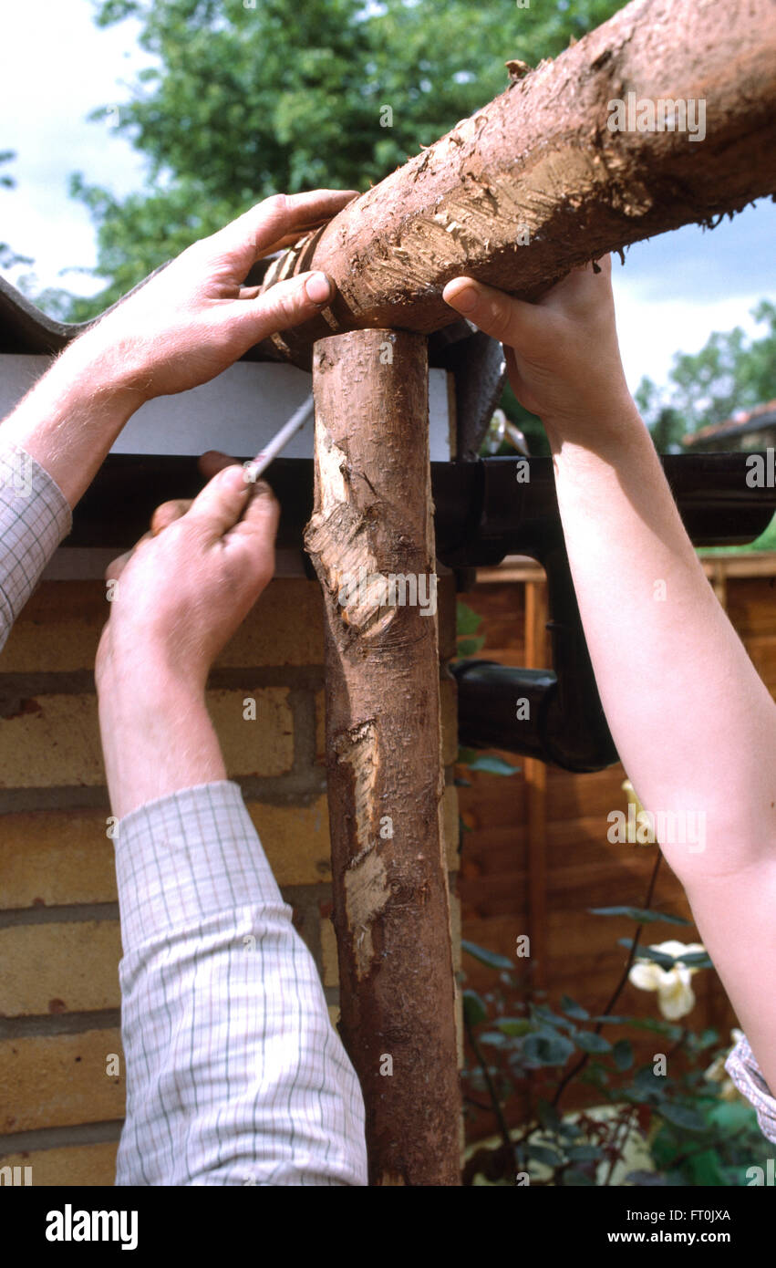 Nahaufnahme der Hände passend eine rustikale Pergola aus Holz Stockfoto