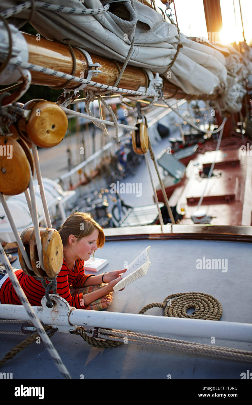 Teenager liegen auf Deck Segelschiff beim Lesen eines Buches, Lauterbach, Putbus, Insland der Rügen, Mecklenburg-Western Pomerania, Deutschland Stockfoto