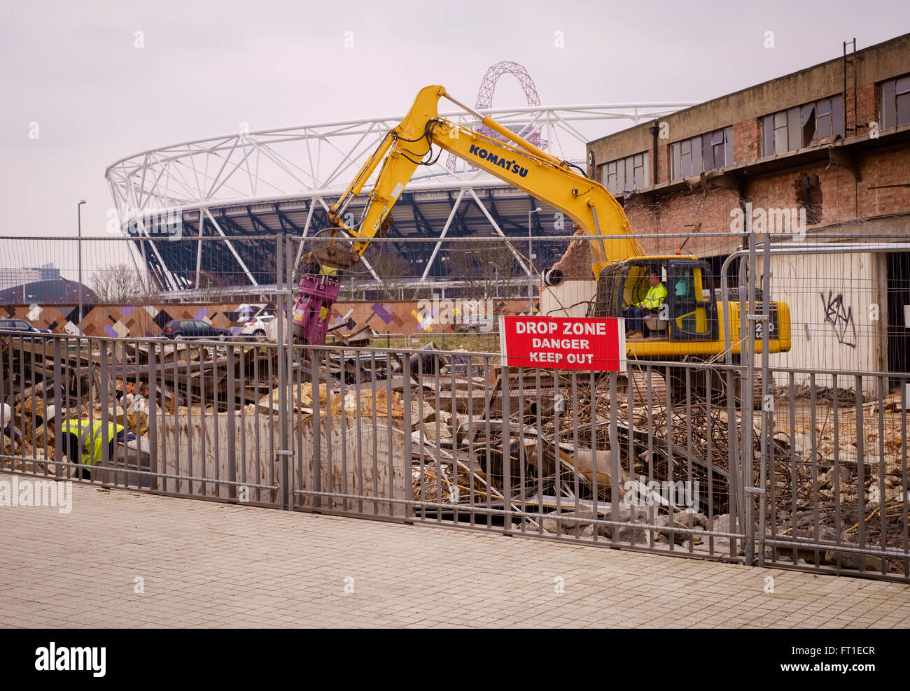 Bulldozer zerstören Lagerhallen für Sanierungen in East London, im Schatten des Olympiastadions Stockfoto