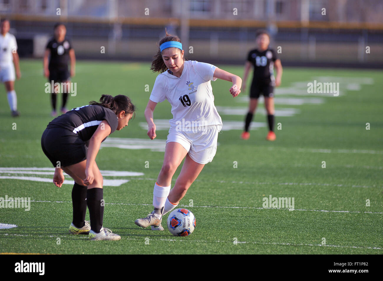 Ein High School Spieler dribbeln in einer Bemühung um ein Verteidiger zu verhandeln, als sie tief in die angreifende Zone eindringt. USA. Stockfoto