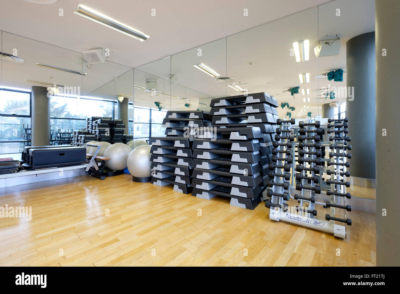 Leere Turnhalle mit einem Rack an Hanteln, Pilates Bällen und haufenweise Schritte Stockfoto