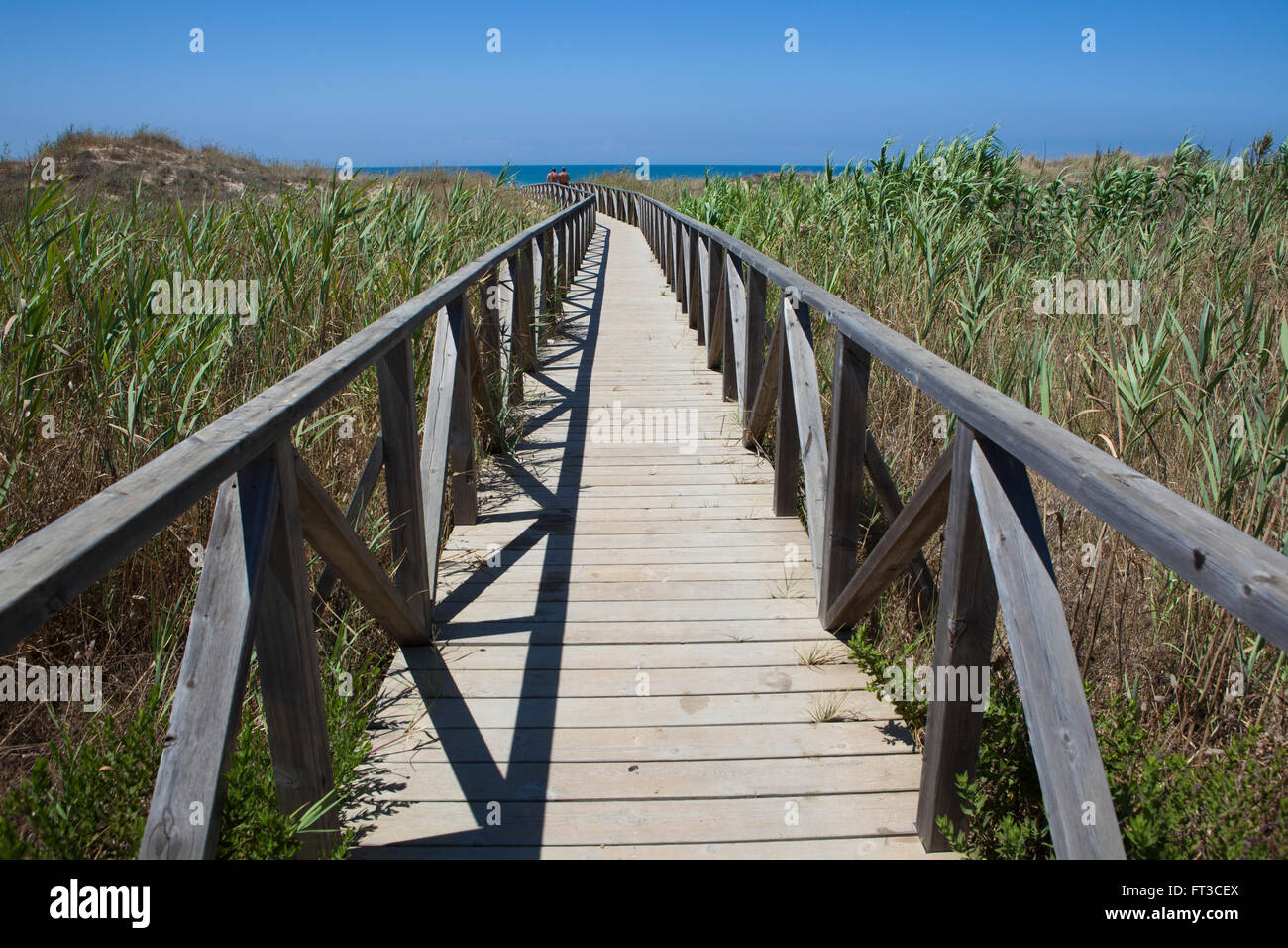 Ein hölzerner Fuß Weg oder Promenade überqueren die niedrigen Sanddünen zu einem Sandstrand an der Südküste von Spanien. Stockfoto