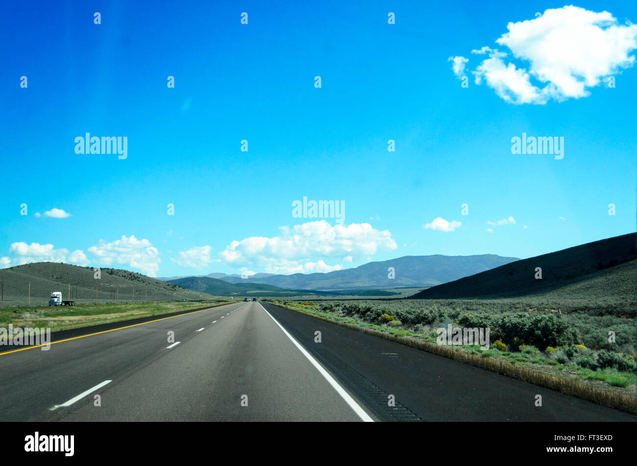 Autobahn durch die offene Landschaft, blauer Himmel und weiße Wolken. Stockfoto