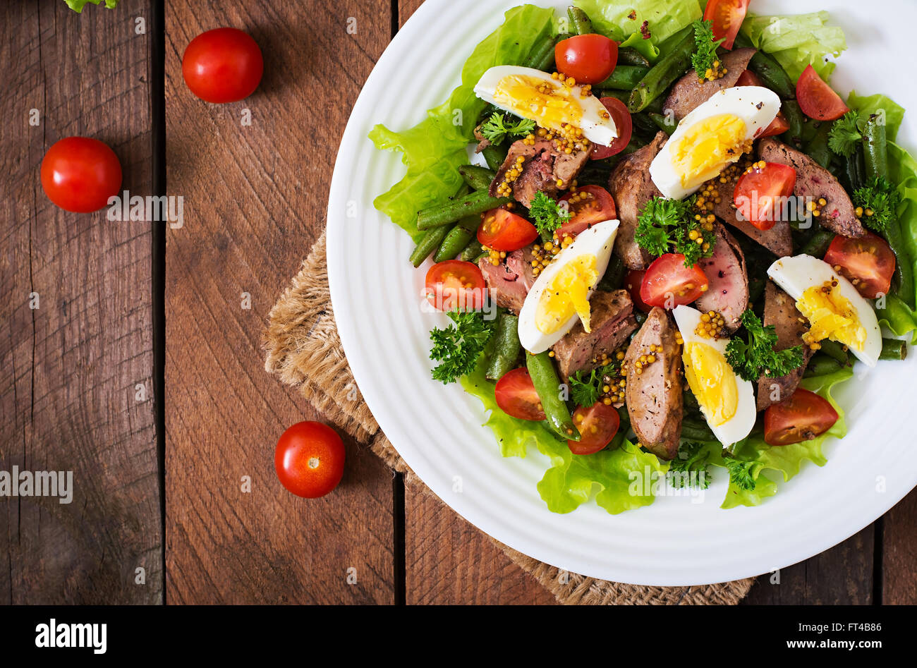 Warmer Salat mit Geflügelleber, grüne Bohnen, Eiern, Tomaten und Balsamico-Dressing. Ansicht von oben Stockfoto