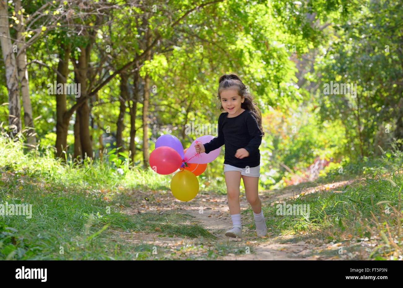 Kleine Mädchen spielen im Herbst Park mit Luftballons Stockfoto