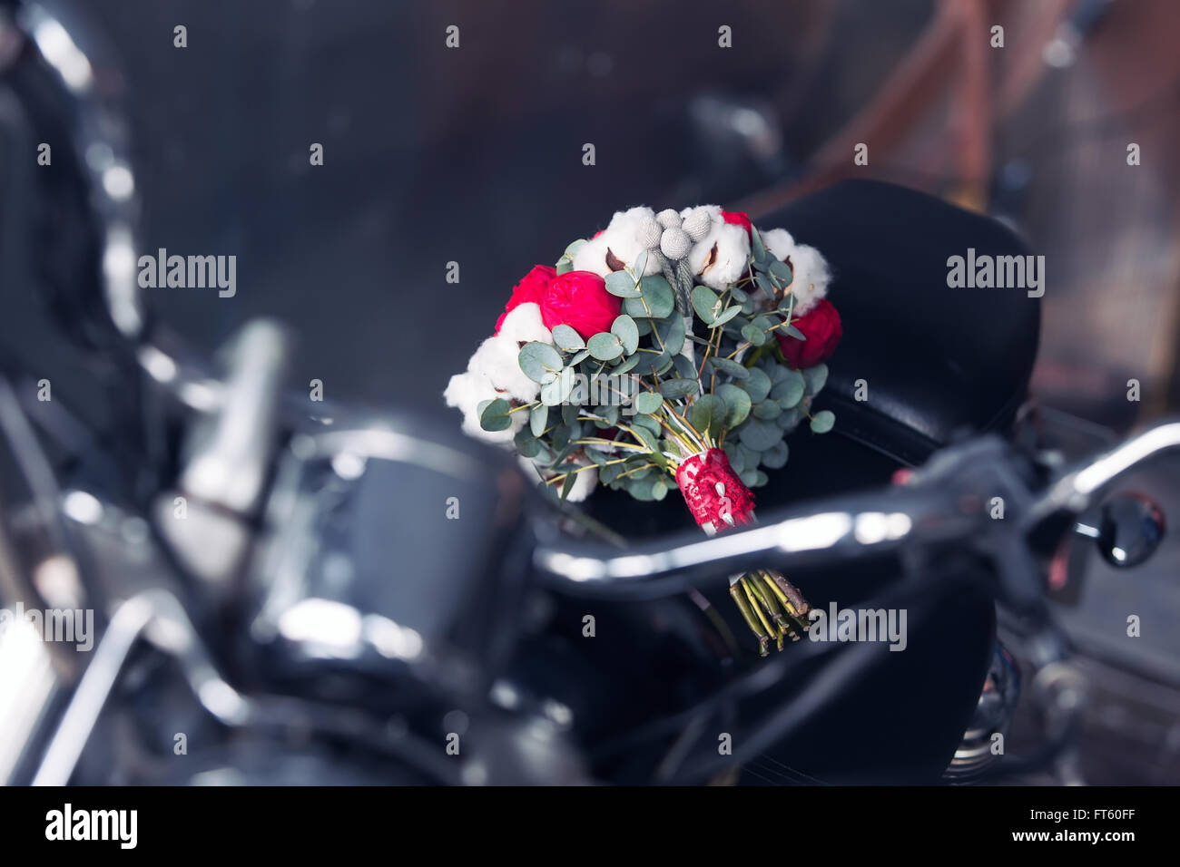 Brautstrauß aus roten Rosen und Baumwolle auf dem Motorrad Stockfoto